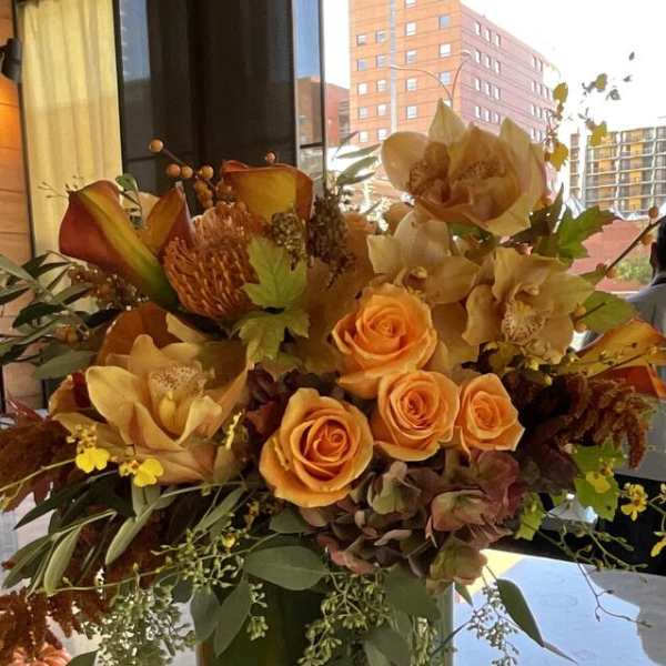 Orange roses and autumn flowers arranged in a green vase