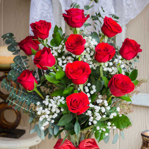 Bouquet of red roses in a glass vase with a red ribbon