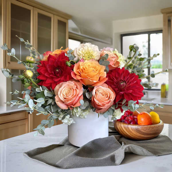 Bouquet of red, peach, and white flowers in a white vase