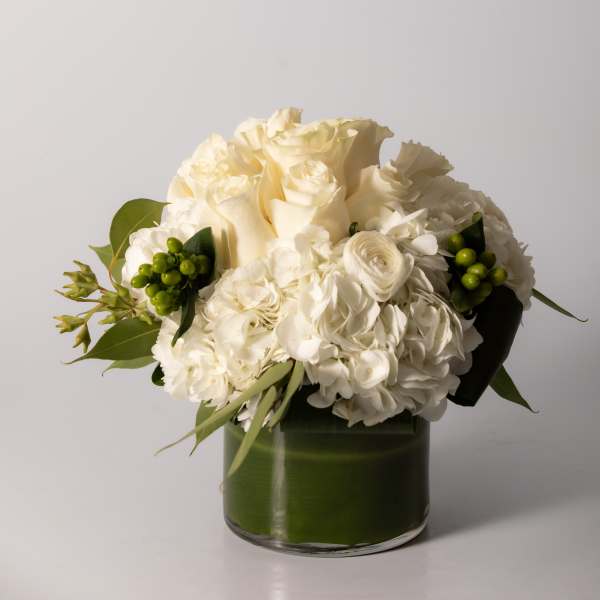 White rose and hydrangea bouquet in a green glass vase