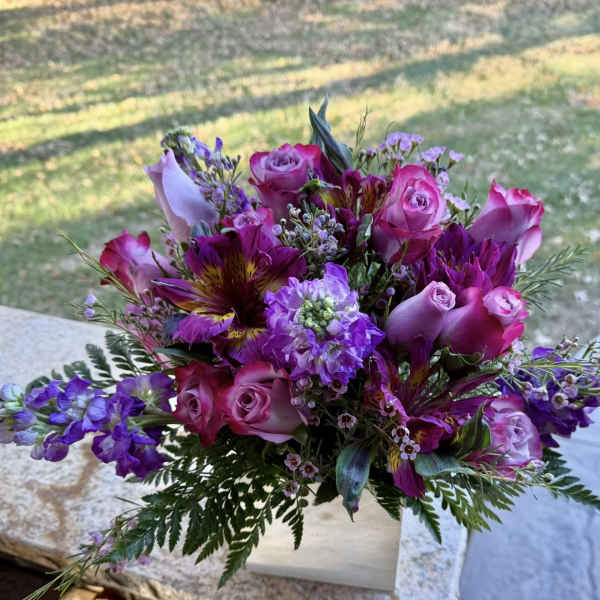 Pink and purple bouquet with roses and mixed blooms in a white box