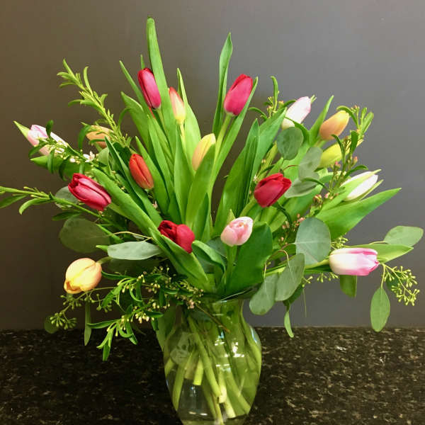 Bouquet of multicolored tulips in a clear glass vase