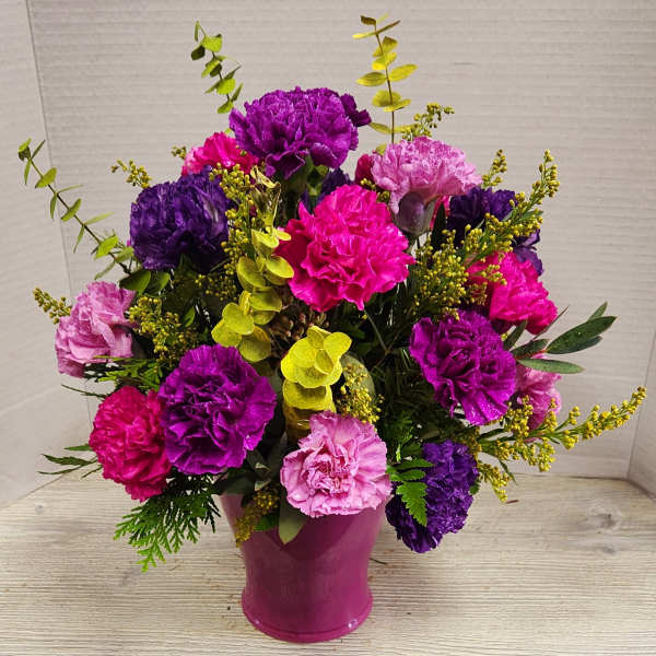 Pink and purple carnations arranged in a magenta vase