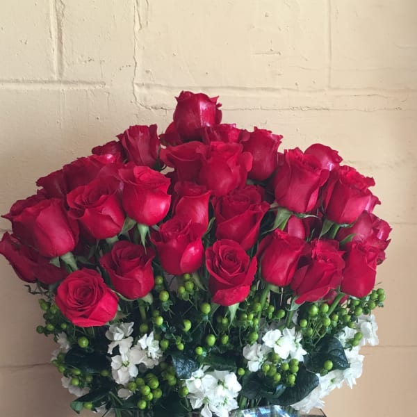 Bouquet of red roses and white flowers in a round glass vase