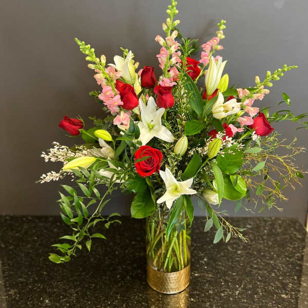 Red roses and white lilies in a glass vase with pink snapdragons