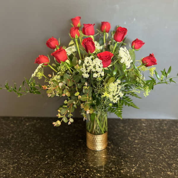 Red roses arranged in a clear vase with white filler flowers