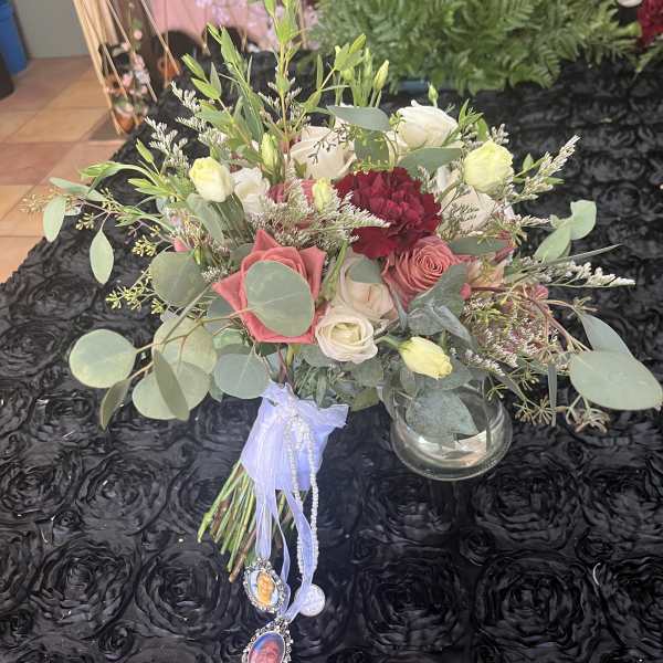 Bouquet of pink, white, and burgundy flowers with a ribbon and photo charms