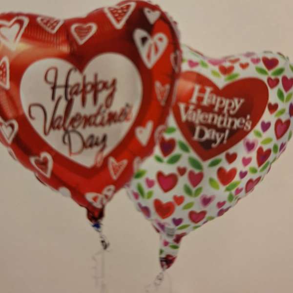 Two heart-shaped Valentine’s Day balloons with printed messages