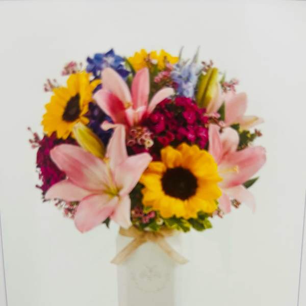 Bouquet of pink lilies and sunflowers in a white vase