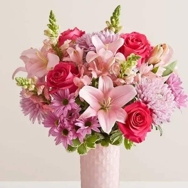 Pink bouquet with roses, lilies, and daisies in a tall pink vase