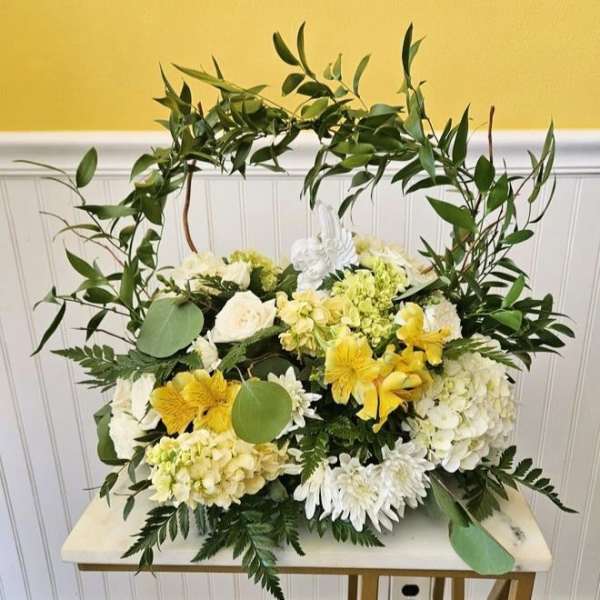 White and yellow floral arrangement with a leafy arch