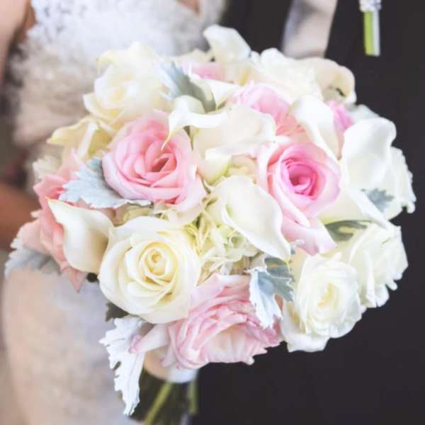 Bride holding a pink and white rose bouquet with a matching boutonniere