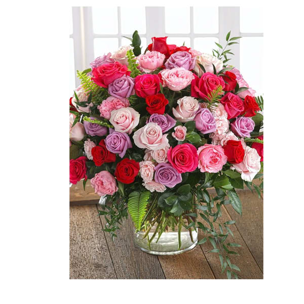 Mixed pink, red, and lavender roses in a clear glass vase