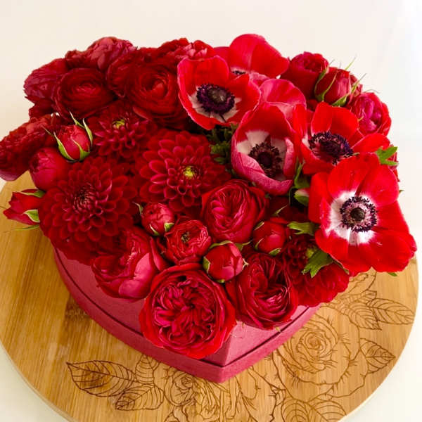 Red floral arrangement in a pink heart-shaped box