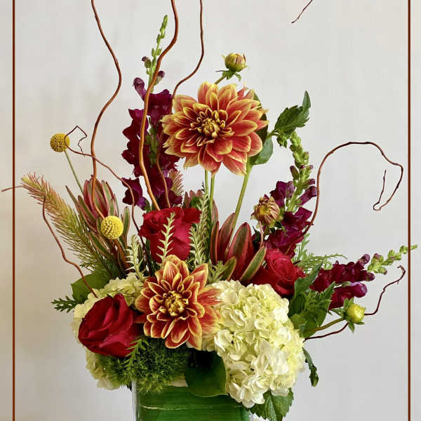 Mixed floral arrangement in a glass vase with red, orange, and white blooms