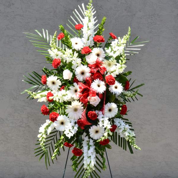 Standing floral spray with white daisies and red carnations on an easel