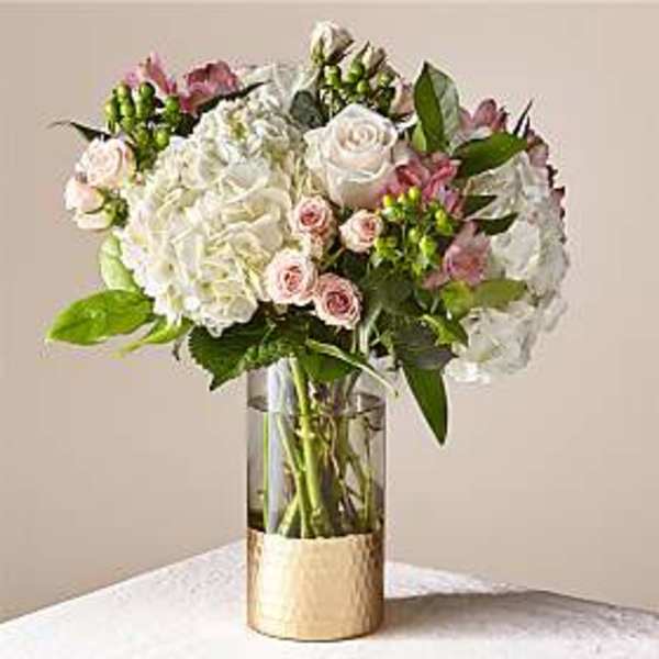 White and blush roses with hydrangeas in a clear glass vase