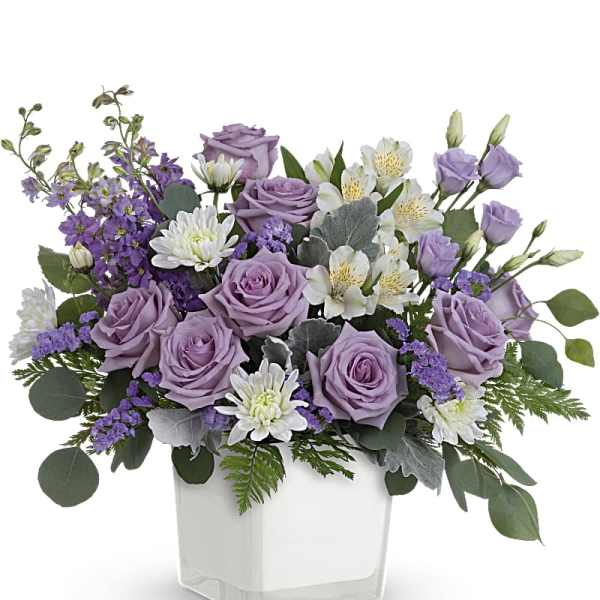 Lavender roses and white flowers in a clear square vase