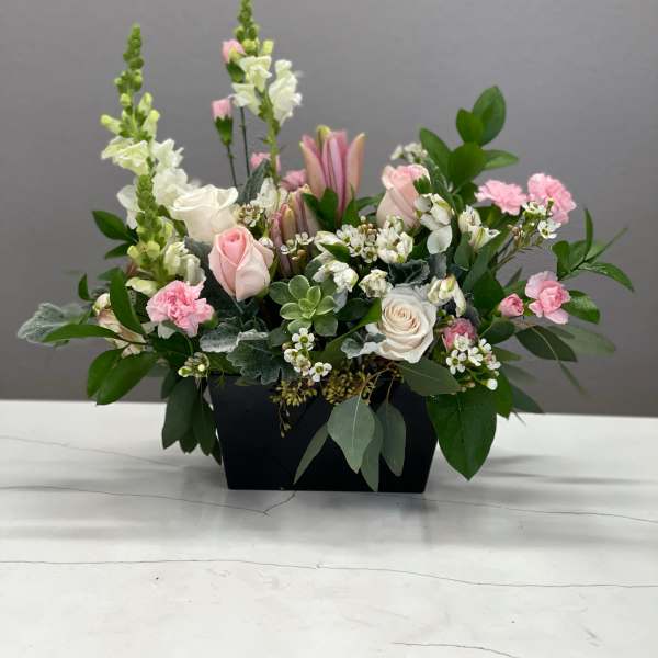 Pink and white floral arrangement in a black container