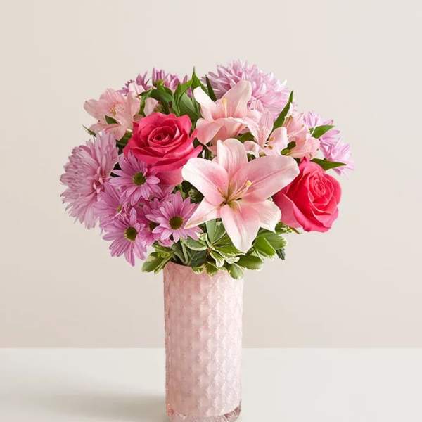 Pink roses and lilies arranged in a tall pink vase