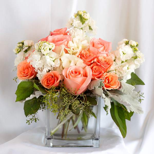 Peach and white roses arranged in a clear glass vase