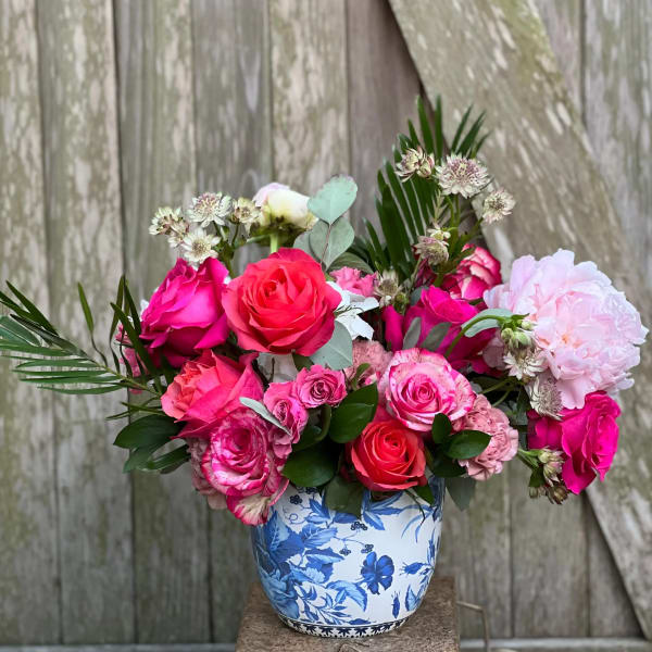 Pink and coral roses arranged in a blue-and-white ceramic vase