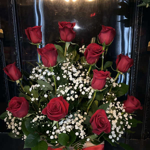 Red roses arranged with white baby's breath in a wooden box tied with a red ribbon
