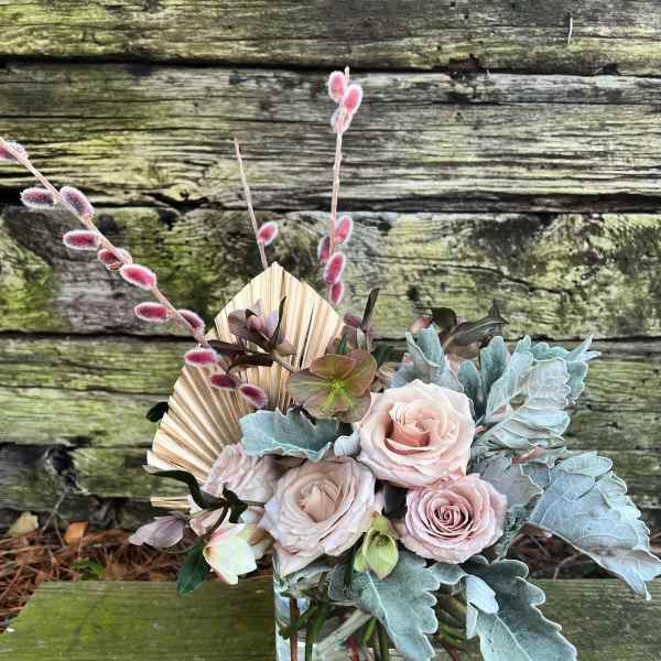 Blush roses in a clear glass vase with blue-gray foliage and pink pussy willow stems