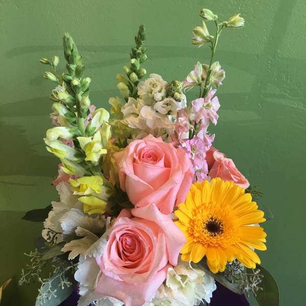 Pink roses and a yellow gerbera daisy in a glass vase