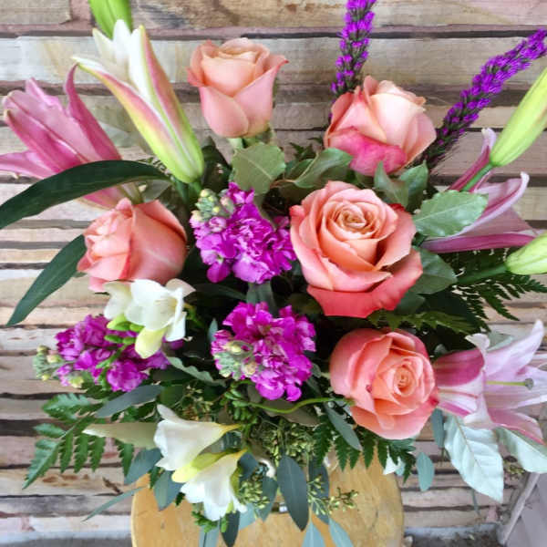 Bouquet of peach roses, lilies, and purple accent flowers