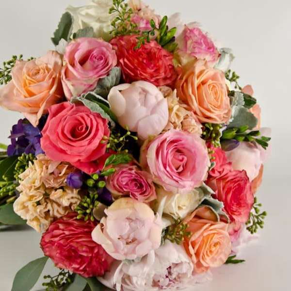 Bouquet of pink, peach, and red roses with mixed blooms
