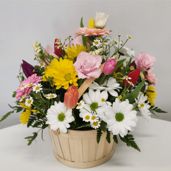 Mixed bouquet of daisies, tulips, and roses in a wooden basket