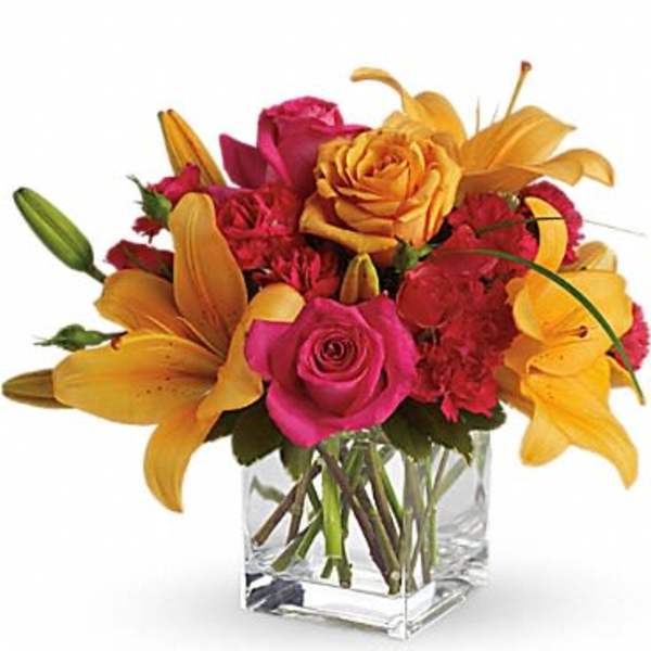 Bouquet of pink roses and yellow lilies in a clear glass vase