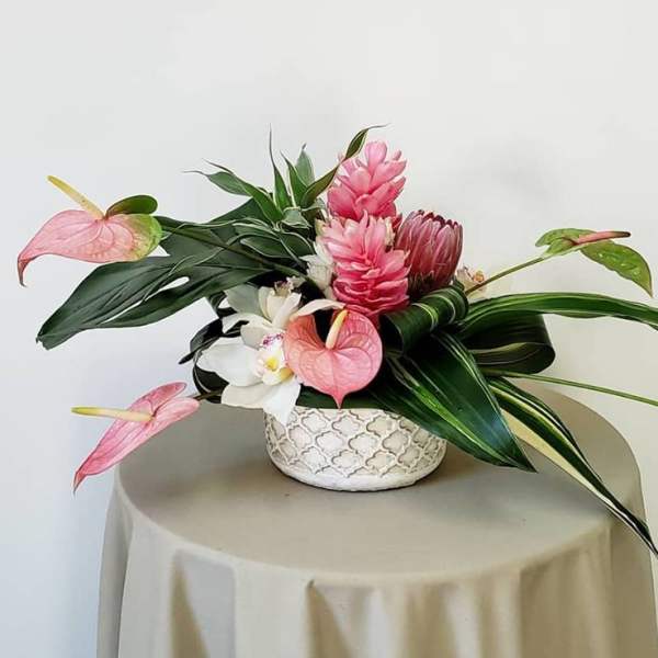 Tropical flower arrangement in a patterned ceramic bowl with pink and white blooms