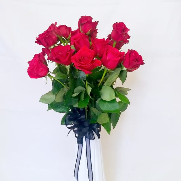 Bouquet of hot pink roses in a white vase with a dark ribbon