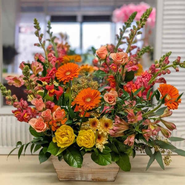 Mixed bouquet in a wooden planter with orange, pink, and yellow flowers
