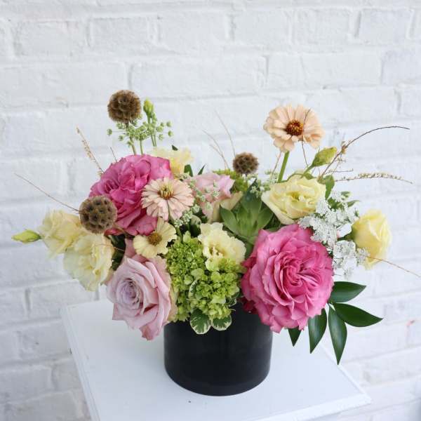 Pink and cream roses arranged in a black vase