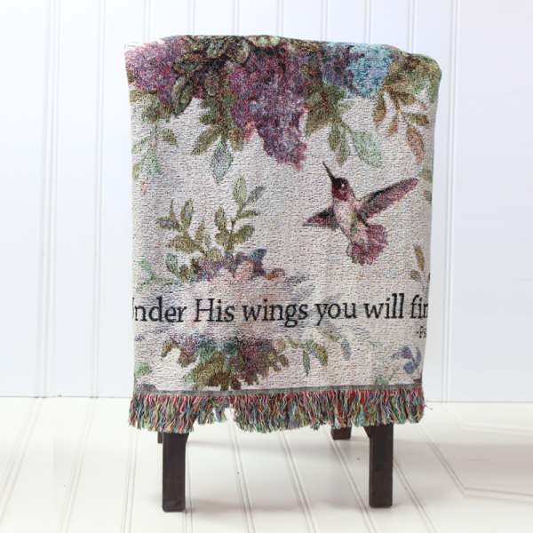 Decorative woven throw with hummingbirds and floral pattern draped over a chair