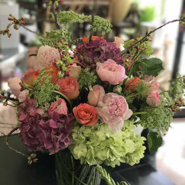 Mixed bouquet of pink, purple, and green flowers in a glass vase