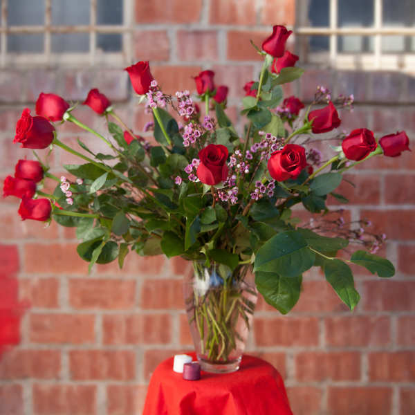 Red roses and pink filler flowers in a clear glass vase
