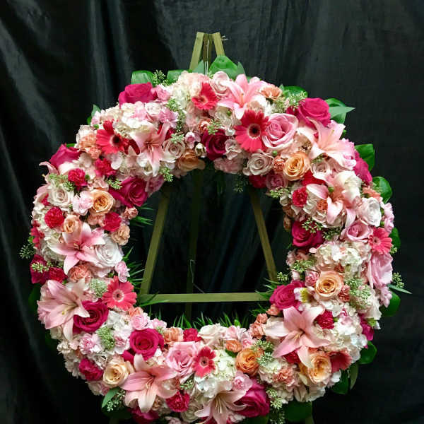 Large floral wreath with pink and white flowers on a stand