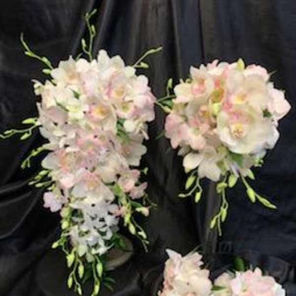 Pastel orchid bouquets with cascading blooms on a dark fabric background