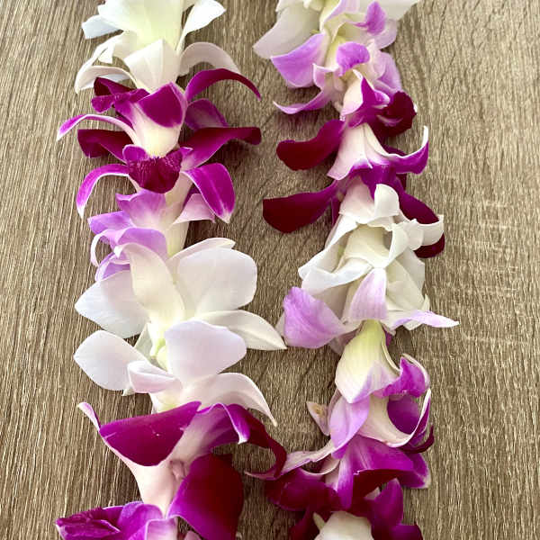 Garland of purple, pink, and white orchid blossoms on a wood surface