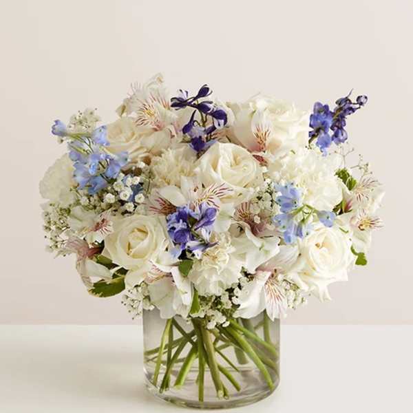 White and blue mixed bouquet in a clear glass vase