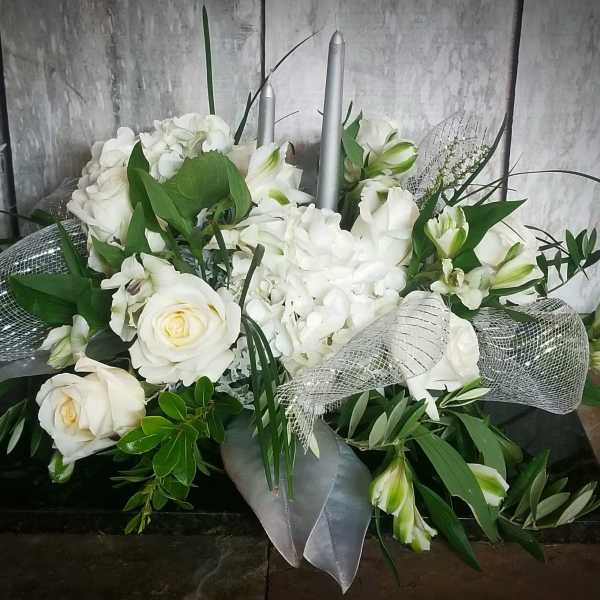 White floral arrangement with roses, hydrangeas, and lilies in a low container