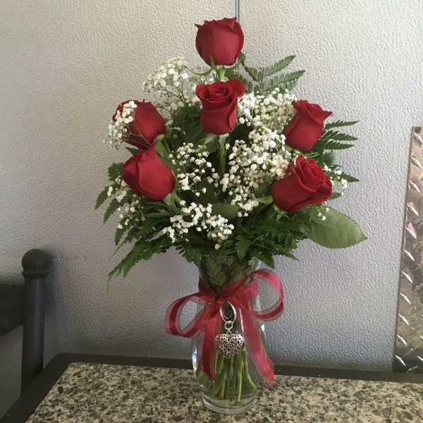 Bouquet of red roses and white baby's breath in a glass vase with a red ribbon
