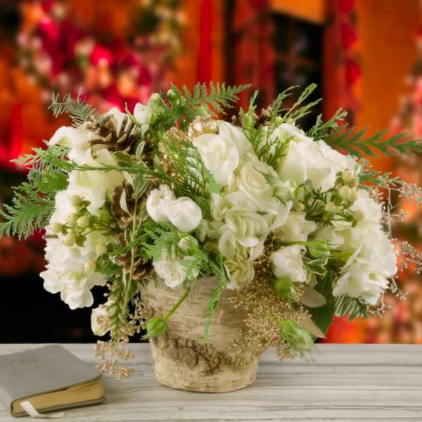 White floral arrangement in a rustic vase beside a book
