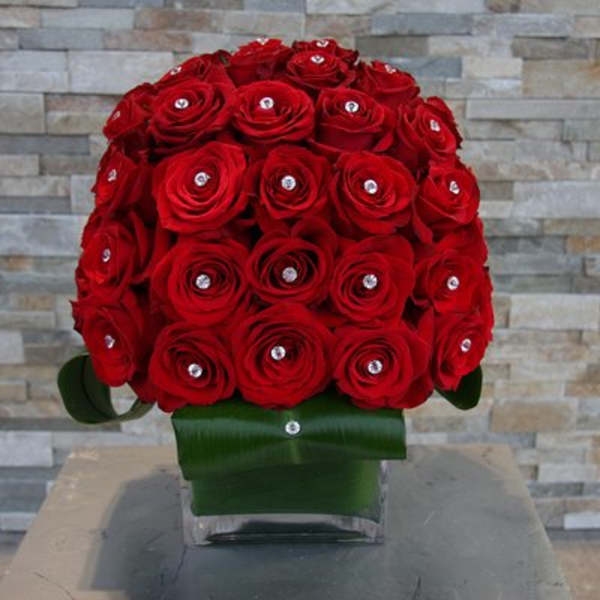 Red rose bouquet in a clear vase with green ribbon wrap
