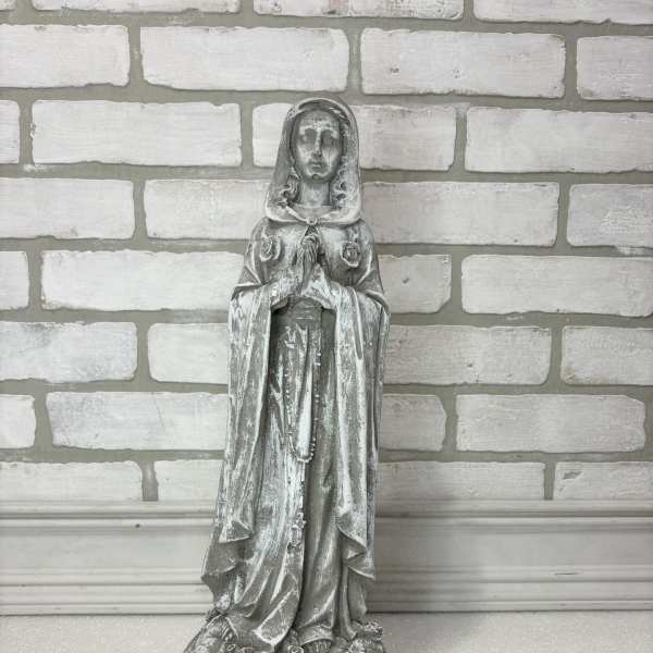 Weathered gray religious statue of a praying woman on a base