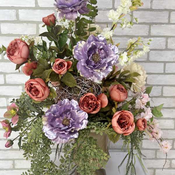 Large floral arrangement with coral and lavender blooms in a gold vase